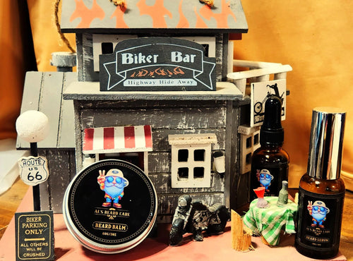 Collection of biker-themed products including a beard balm, bottles, and a miniature bar model on a wooden surface.
